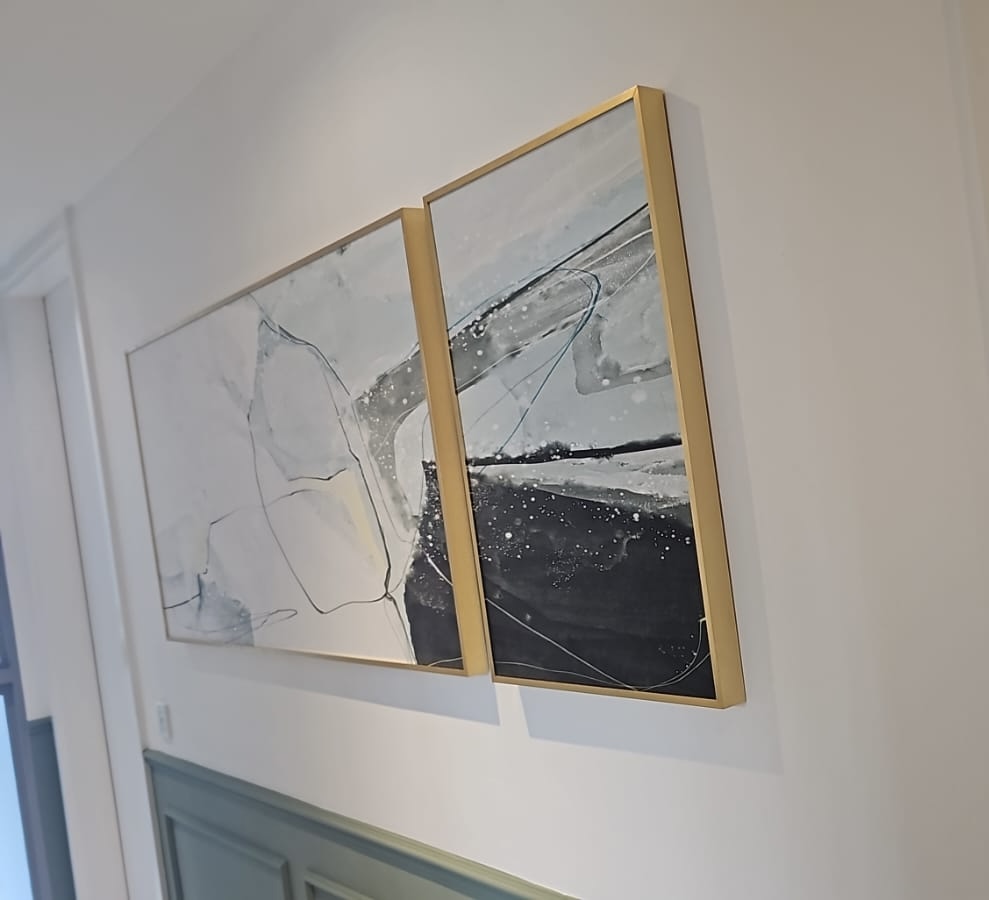 Two gold framed prints hung level in a hallway